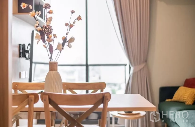 Condominium for rent in Chatuchak, Bangkok - Vase with dried flowers on a wooden dining table beside large curtained windows.