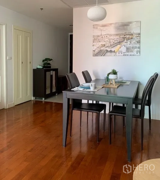 Condominium for rent in Khlong Toei, Bangkok - Open dining area with pendant light, black table and warm wood floors.