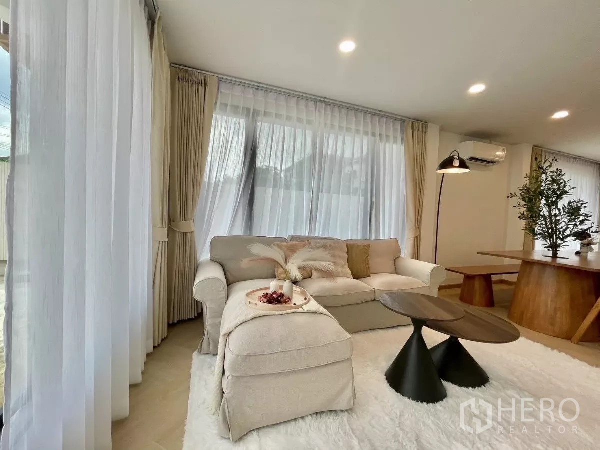 บ้าน ขายในPrawet, Bangkok - ห้องนั่งเล่นสว่าง โซฟาสีครีม โต๊ะกาแฟทรงกลม ม่านโปร่งและไฟดาวน์ไลท์