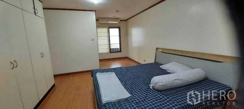 Condominium for rent in Khlong Toei, Bangkok - Third bedroom with checkered bedding, built‑in wardrobe, wood flooring, window and air conditioning.