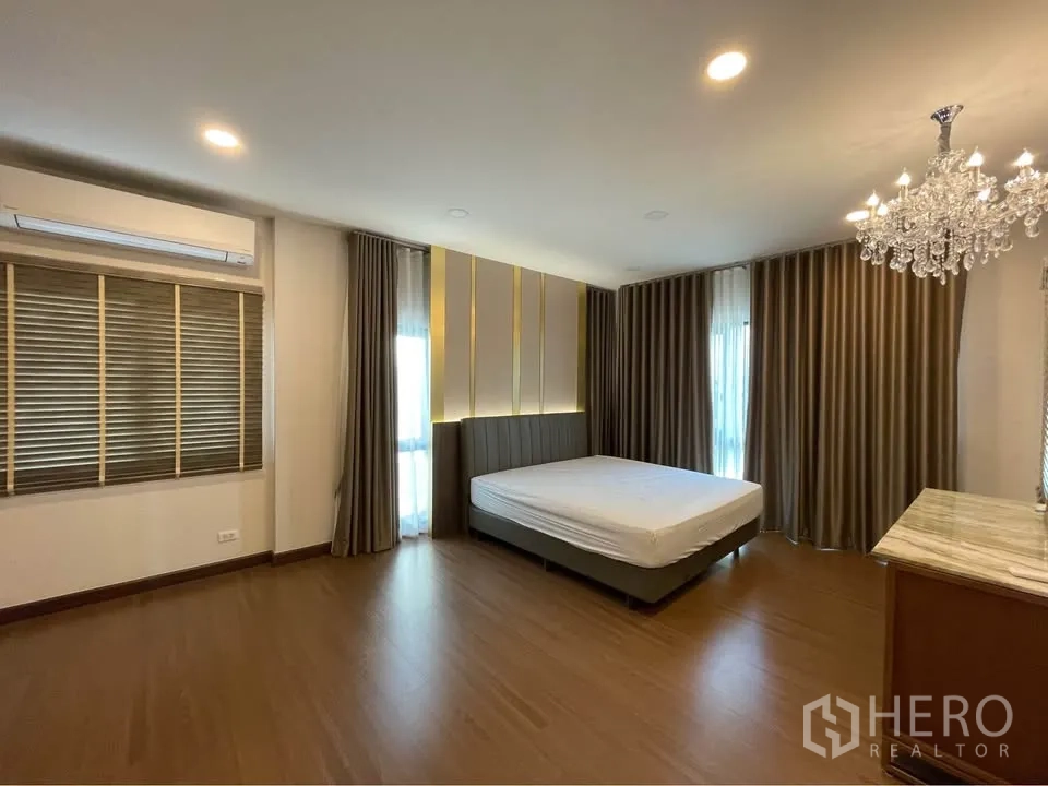 独栋房屋 for rent or sale in Bang Phli, Samut Prakan - 宽敞主卧配水晶吊灯、落地窗与窗帘。