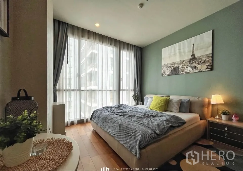 Condominium for rent in Watthana, Bangkok - Bedroom with large windows, king bed, accent wall and soft lighting.