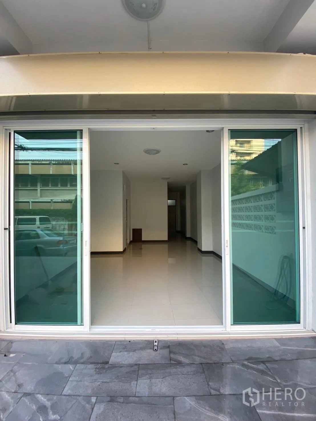 Townhouse for rent in Huai Khwang, Bangkok - Ground-floor entry showing large green-tinted sliding doors opening to a bright open-plan area.