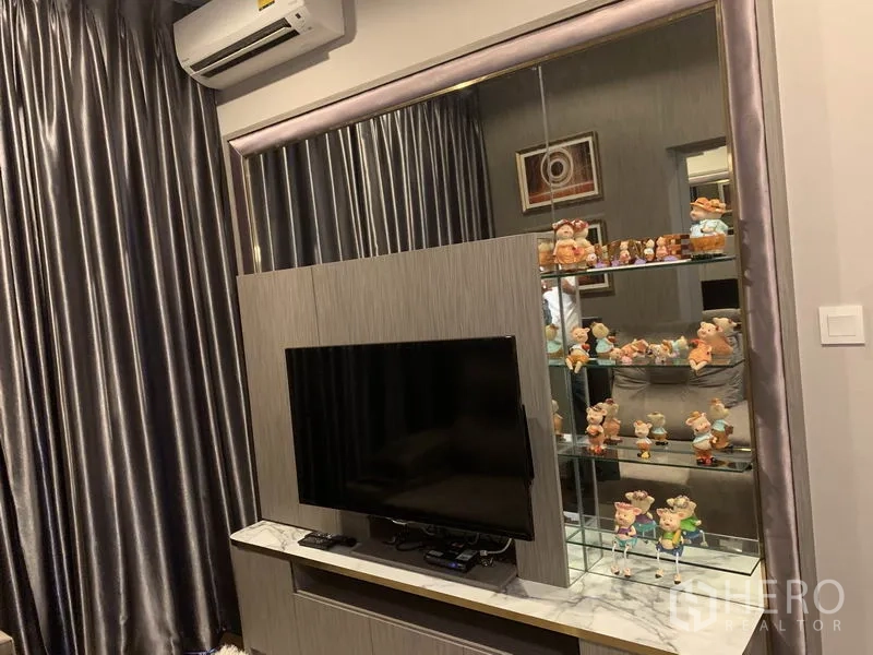 คอนโด ขายในWatthana, Bangkok - พื้นที่นั่งเล่นมีผนังทีวีบิวท์อิน ตู้โชว์กระจก และผ้าม่านทึบ ในคอนโดเขตวัฒนา.