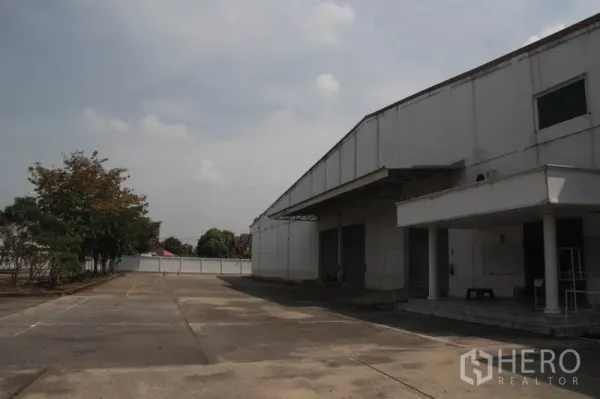 货栈 出租在Lam Luk Ka, Pathum Thani - Lam Luk Ka 大型白色仓库外观，带雨棚与宽阔装卸区。