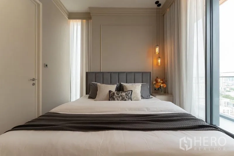 Condominium for rent in Watthana, Bangkok - Master bedroom front view with upholstered headboard and full-height window to balcony.