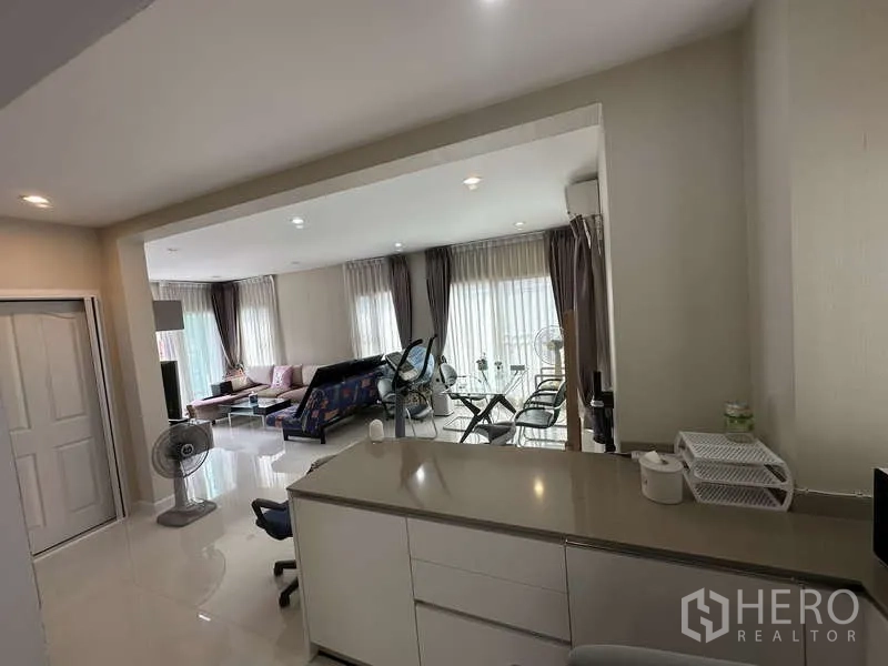 Detached House for sale in Sai Mai, Bangkok - Kitchen pass-through looking into the bright living area with curtains.