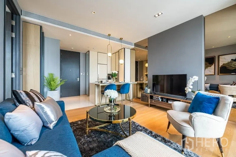 Condominium for rent or sale in Khlong Toei, Bangkok - Open-plan living and dining area with TV console and round coffee table.