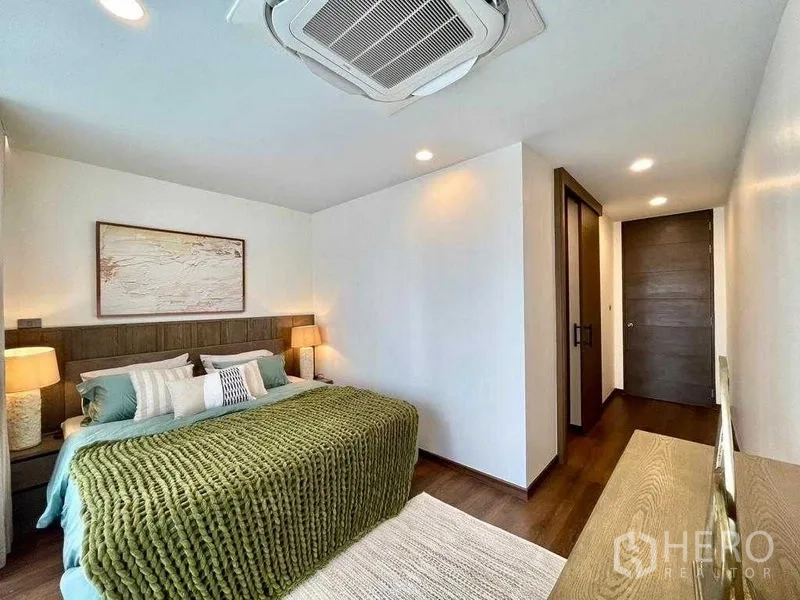 独立式住宅 出租在Bang Rak, Bangkok - 温馨卧室，绿色毛毯、床头灯与木地板