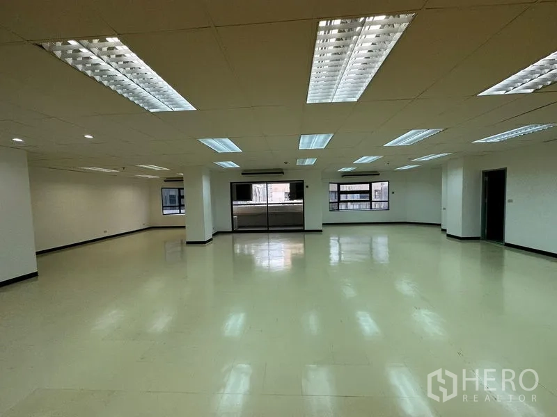 办公空间 出租在Pathum Wan, Bangkok - 宽敞开放式办公区，天花多组荧光灯，侧面多窗与中央立柱。