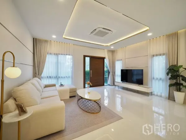 独立式住宅 出租在Bang Phli, Samut Prakan - 采光充足的客厅，L形沙发、电视柜与大窗。