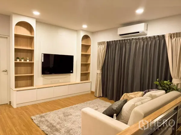 บ้าน ให้เช่าในBang Phli, Samut Prakan - ห้องนั่งเล่นบิลท์อินชั้นวางทีวี พื้นไม้ พร้อมผ้าม่านทึบและไฟดาวน์ไลท์