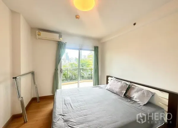 公寓 出租在Huai Khwang, Bangkok - 主卧带阳台门与大窗，享绿意与城市天际线景观。