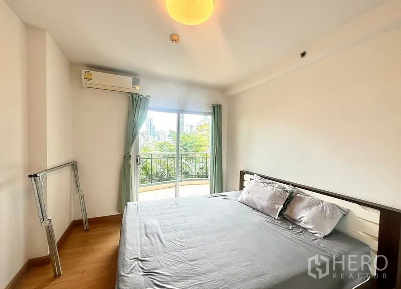 公寓 出租在Huai Khwang, Bangkok - 主卧带阳台门与大窗，享绿意与城市天际线景观。