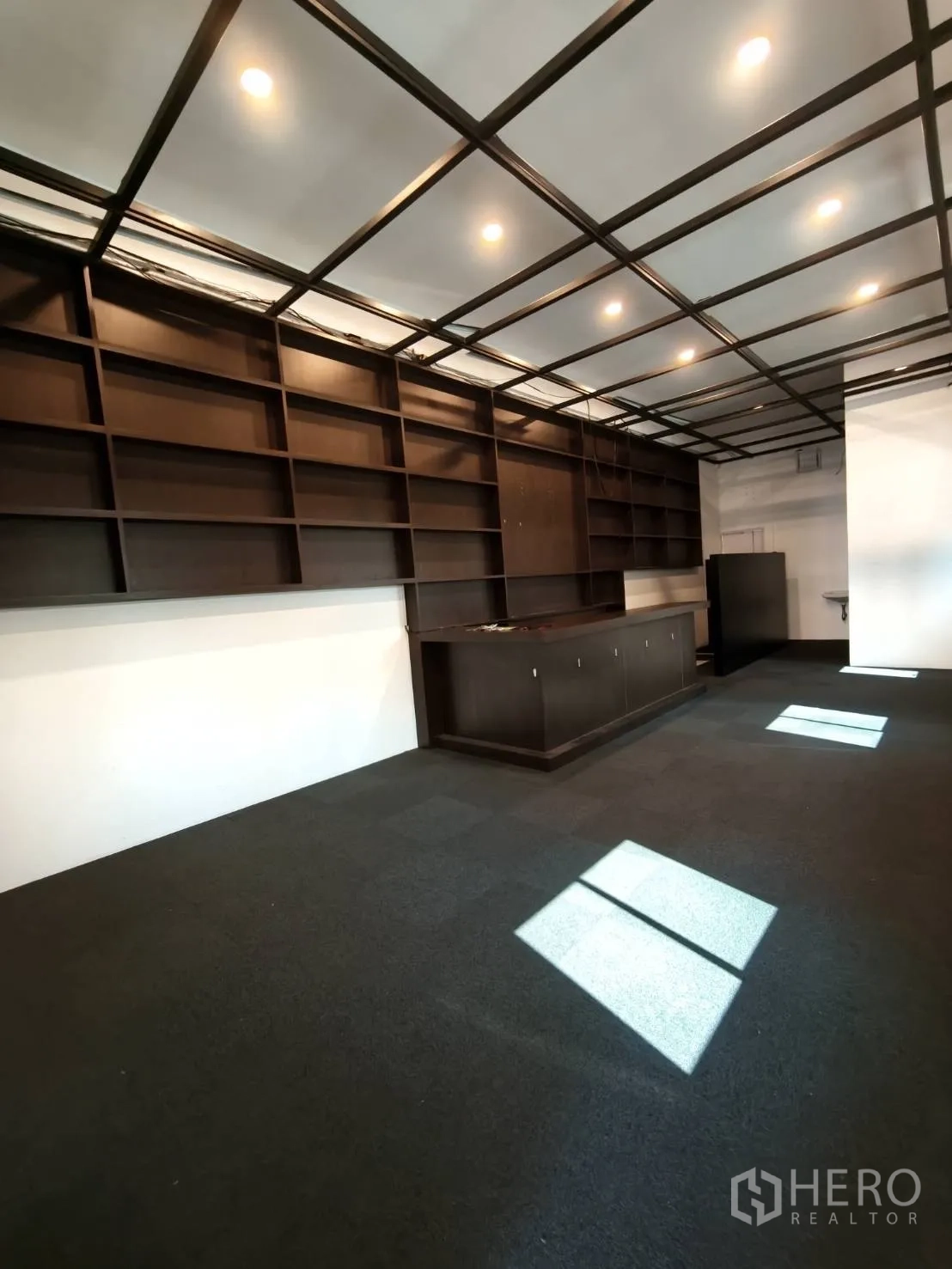 零售空间 for rent in Watthana, Bangkok - 开放式零售区，网格天花嵌灯、搁架与服务吧台。