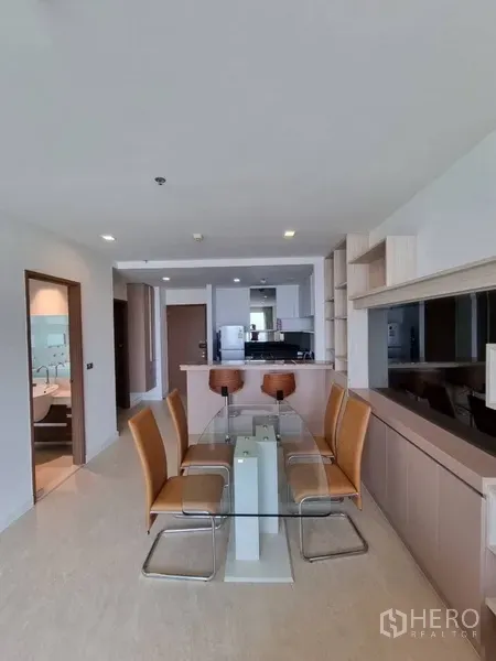 Condominium for rent in Watthana, Bangkok - Glass-top dining table for six beside the open kitchen and guest bathroom entrance.