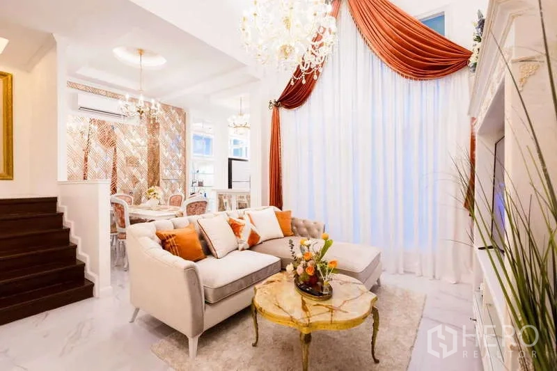 Townhouse for rent in Lat Phrao, Bangkok - Elegant living and dining area with crystal chandeliers, marble flooring and full-height curtains.