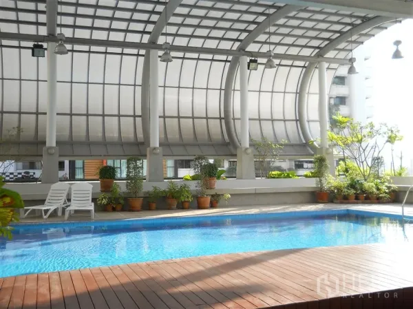 Condominium for rent in Watthana, Bangkok - Covered swimming pool with wooden deck, potted plants and lounge chairs