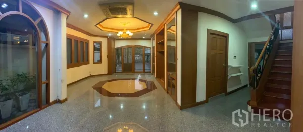 Detached House for rent in Watthana, Bangkok - Spacious open-plan living hall with glossy floor, wood trims and staircase.