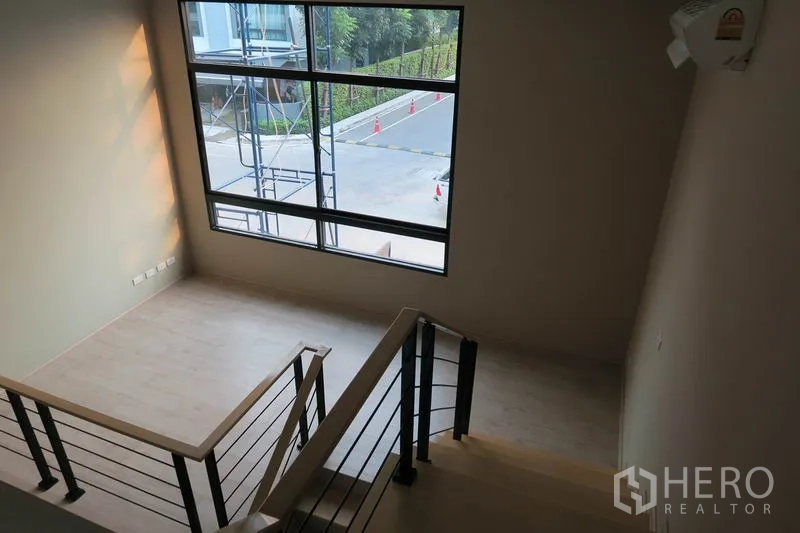 Townhouse for rent in Suan Luang, Bangkok - Upper landing with a big picture window overlooking a quiet townhouse street.