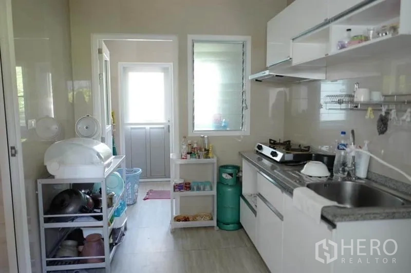 独立式住宅 出售在Pak Kret, Nonthaburi - 厨房走廊通往后勤门，设置置物架与窗户。