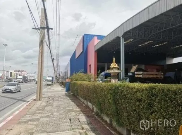 Warehouse for rent in Khlong Luang, Pathum Thani - Street-front warehouse in Khlong Luang with covered loading bay and hedge frontage.