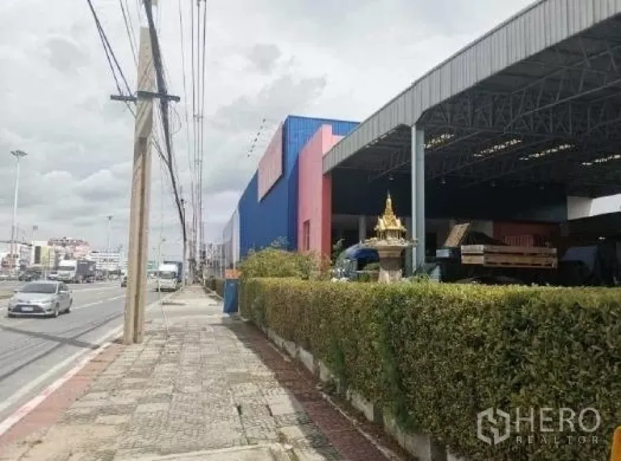 Warehouse for rent in Khlong Luang, Pathum Thani - Street-front warehouse in Khlong Luang with covered loading bay and hedge frontage.