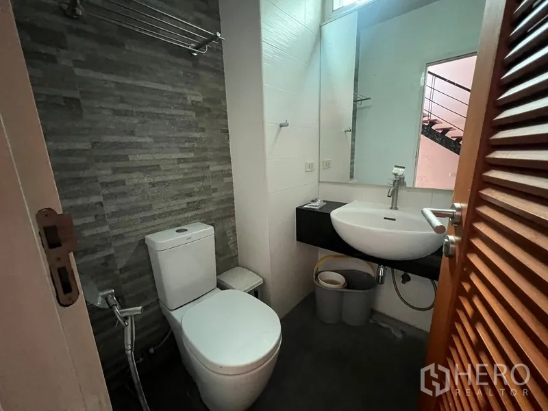 Townhouse for rent in Din Daeng, Bangkok - Guest bathroom with vessel sink, mirror and toilet beside the stairs.