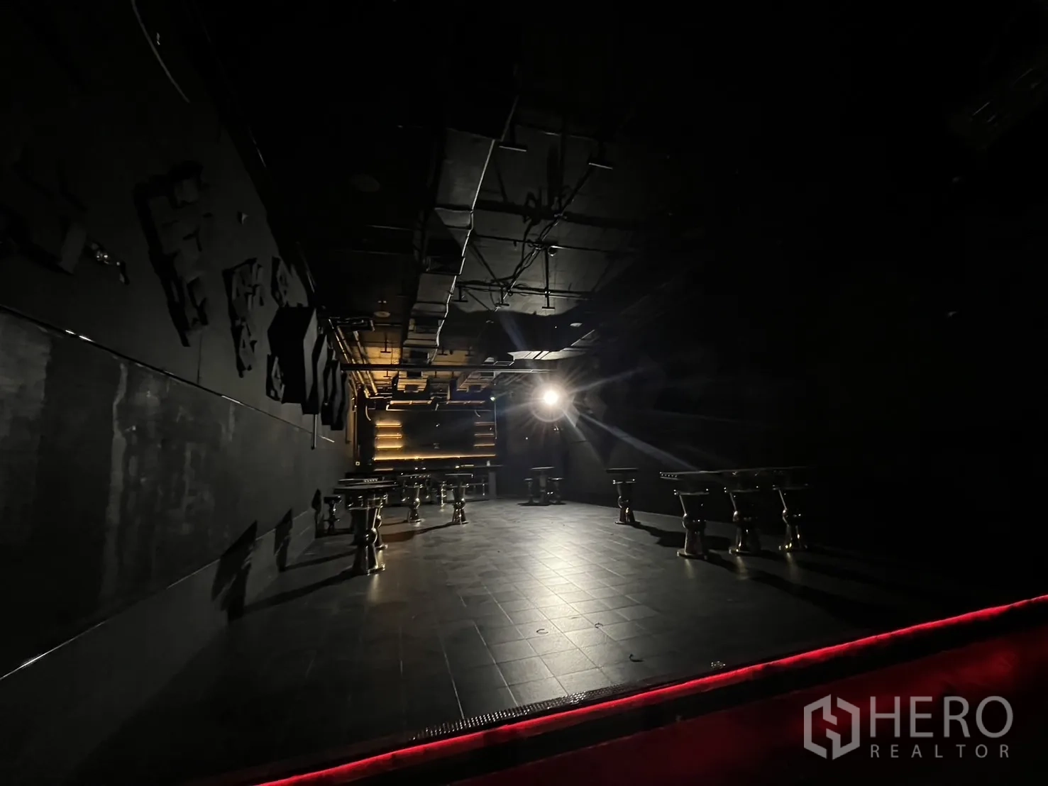 Retail Space for rent - Spacious black-tiled hall with a central spotlight and exposed industrial ceiling.