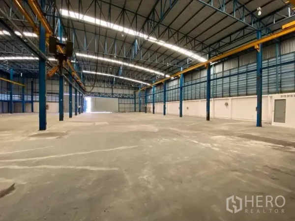 Factory for rent or sale in Bang Sao Thong, Samut Prakan - Spacious factory interior with high steel truss roof, concrete floor, and overhead crane rails.