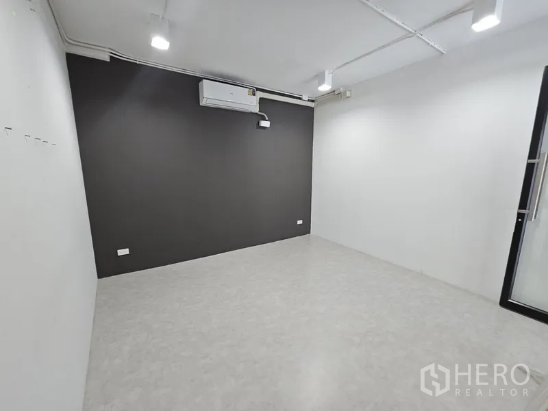 Retail Space for rent - Clean workspace with gray accent wall, mounted air conditioner, and glossy tile floor.