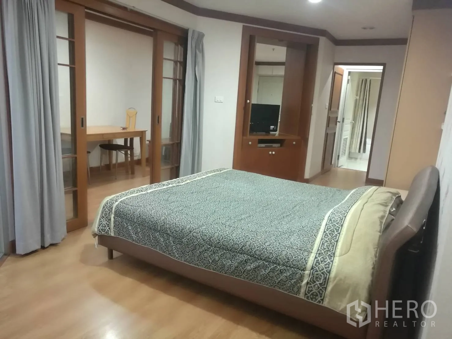 Condominium for rent in Khlong Toei, Bangkok - Spacious bedroom with double bed, built-ins and sliding doors to a study nook.