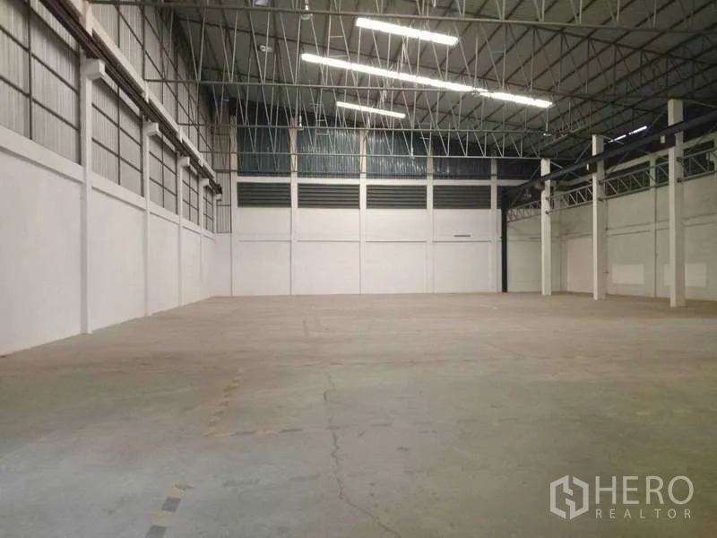 Factory for rent in Mueang Samut Prakan, Samut Prakan - Large open manufacturing space with concrete floor, bright strip lighting and column grid.