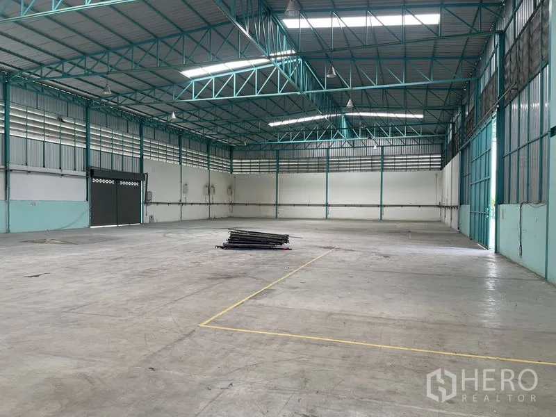 货栈 出租在Lat Lum Kaeo, Pathum Thani - 仓库大厅设有大型卷闸门、天花照明与划线作业区。
