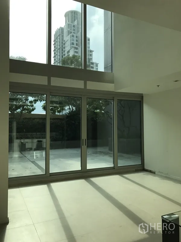 公寓 出租在Khlong San, Bangkok - 挑高客厅，落地推拉门通向大露台，可见城市与绿景