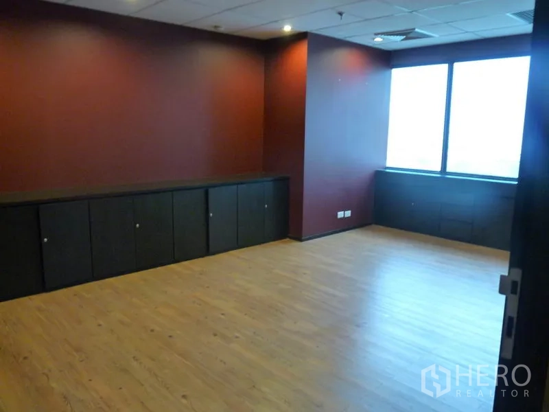 Office Space for sale in Watthana, Bangkok - Corner executive room with red accent wall, large window and low built-in cabinets.