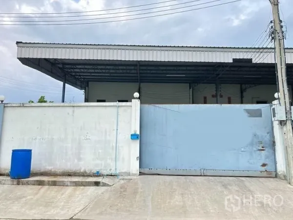 Factory for rent in Samut Prakan - Gated factory entrance with high concrete wall, sliding metal gate and covered loading roof in Bang Phli.