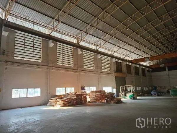 Factory for rent in Mueang Samut Prakan, Samut Prakan - Open production floor with large louver windows, skylights, and organized storage areas.