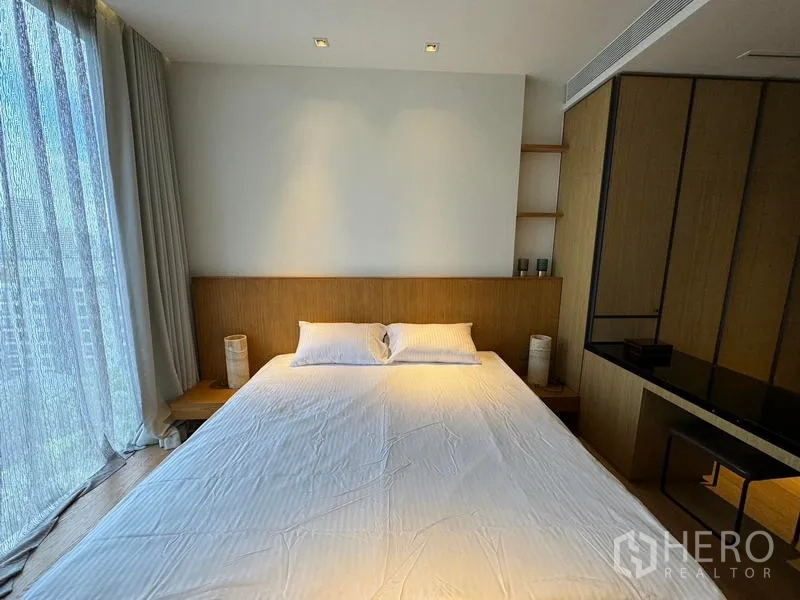 Condominium for rent in Khlong Toei, Bangkok - Sunlit bedroom with king-size bed, sheer curtains and warm wood accents.