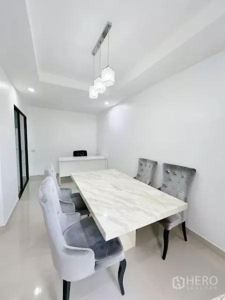 联排别墅 出租在Bang Phli, Samut Prakan - 白色用餐室，吊灯、石纹餐桌和灰色绒面餐椅。
