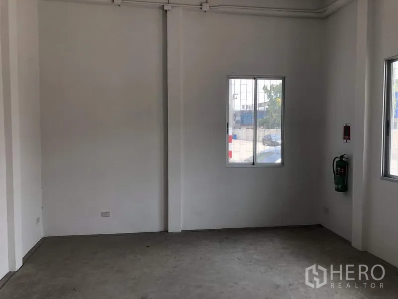 Factory for rent in Khlong Luang, Pathum Thani - Clean white office room with windows and a wall-mounted fire extinguisher.