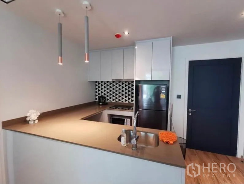 Condominium for rent in Sathon, Bangkok - U-shaped kitchen with white cabinetry, patterned backsplash, built-in hob and sink.