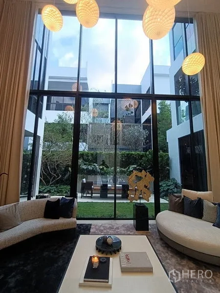 Detached House for sale - Double‑height living room with floor‑to‑ceiling windows opening to landscaped courtyard.