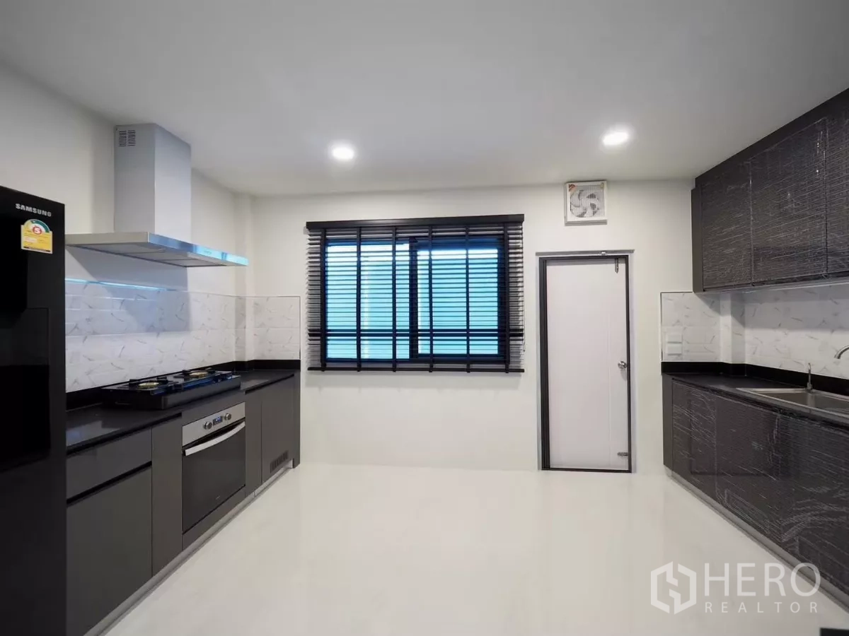 独立式住宅 出租在Bang Phli, Samut Prakan - 配备齐全的泰式厨房，燃气灶、抽油烟机与黑色台面。