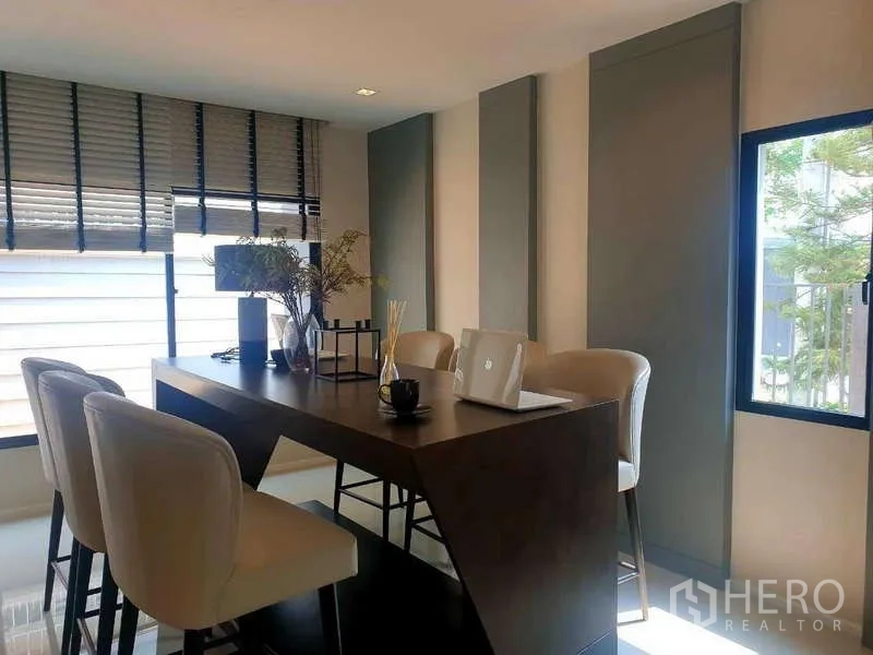 Home Office for rent in Bang Phli, Samut Prakan - Bright meeting corner with a tall island table, upholstered bar stools and wide windows.
