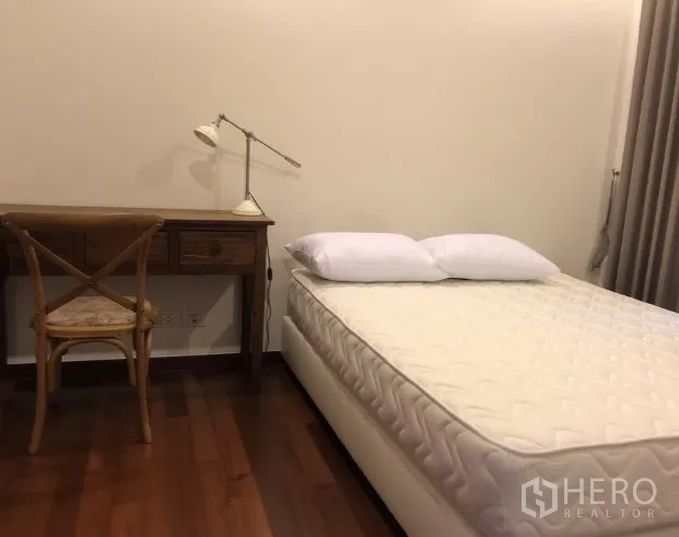 Condominium for rent or sale in Khlong Toei, Bangkok - Cozy bedroom with double bed, curtains, and a wooden desk with reading lamp.