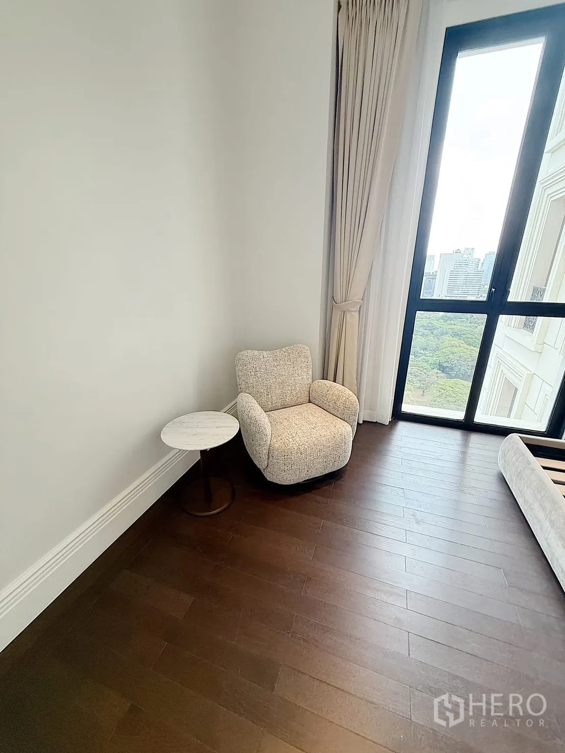 คอนโด for rent or sale in Pathum Wan, Bangkok - มุมพักผ่อนพร้อมเก้าอี้นวมและโต๊ะข้าง ใกล้หน้าต่างสูงและผ้าม่าน