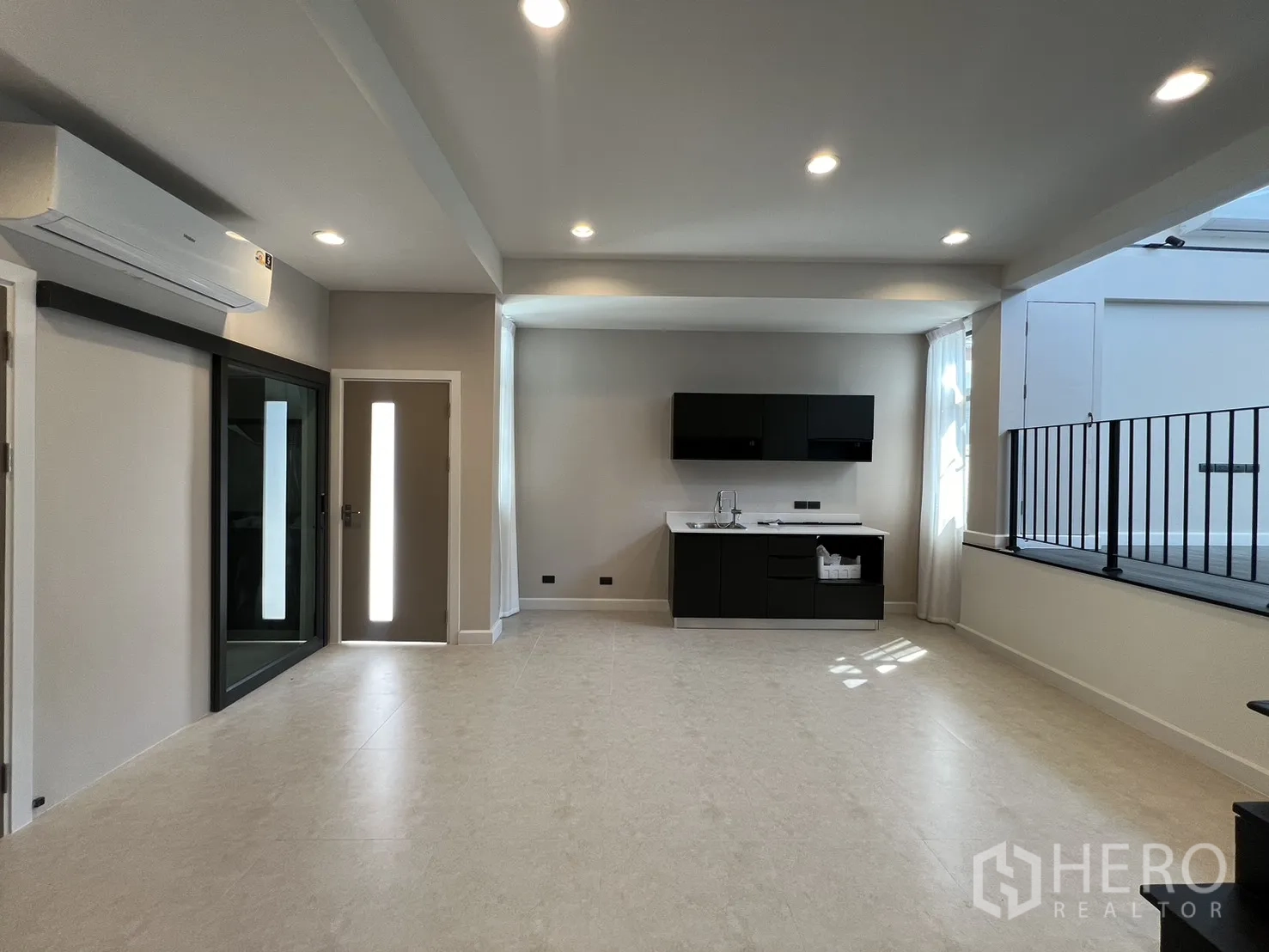 Detached House for rent in Saphan Sung, Bangkok - Spacious room with kitchenette, large windows and glass sliding door over neutral tiled floors.