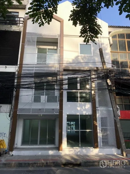 带办公室的家 出租在Khlong Toei, Bangkok - 正立面配穿孔金属屏与挑高玻璃入口。