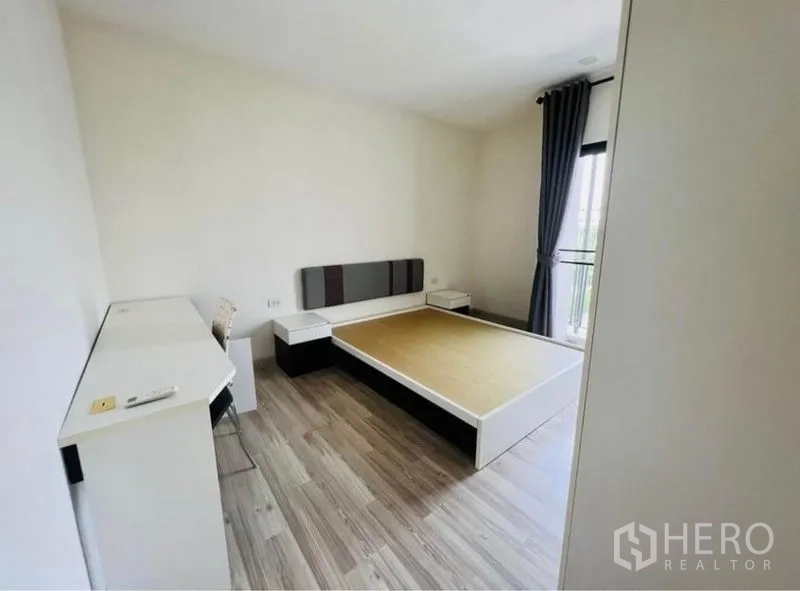 Townhouse for rent in Saphan Sung, Bangkok - Bedroom with platform bed, bedside tables, built-in desk and access to a balcony.